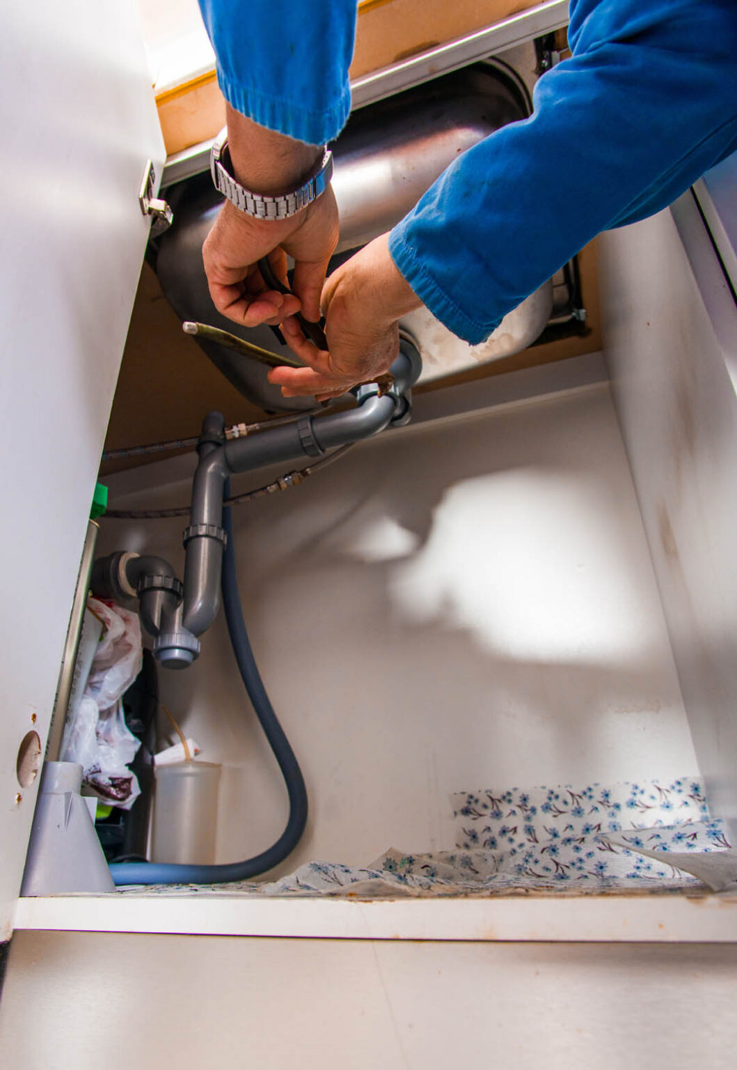 Senior handyman repair pipes on the sink in kitchen